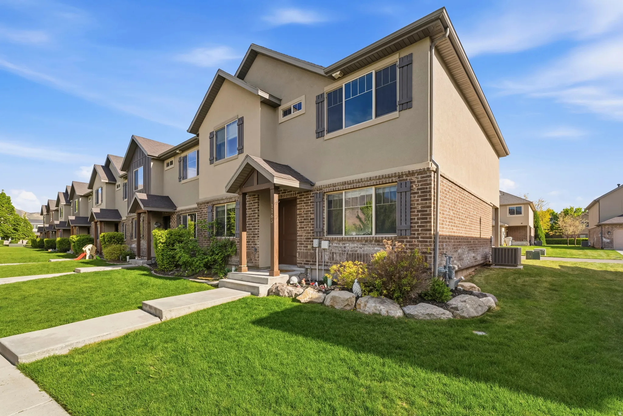 Traditional-style home featuring a front lawn, brick siding, stucco siding, and a residential view