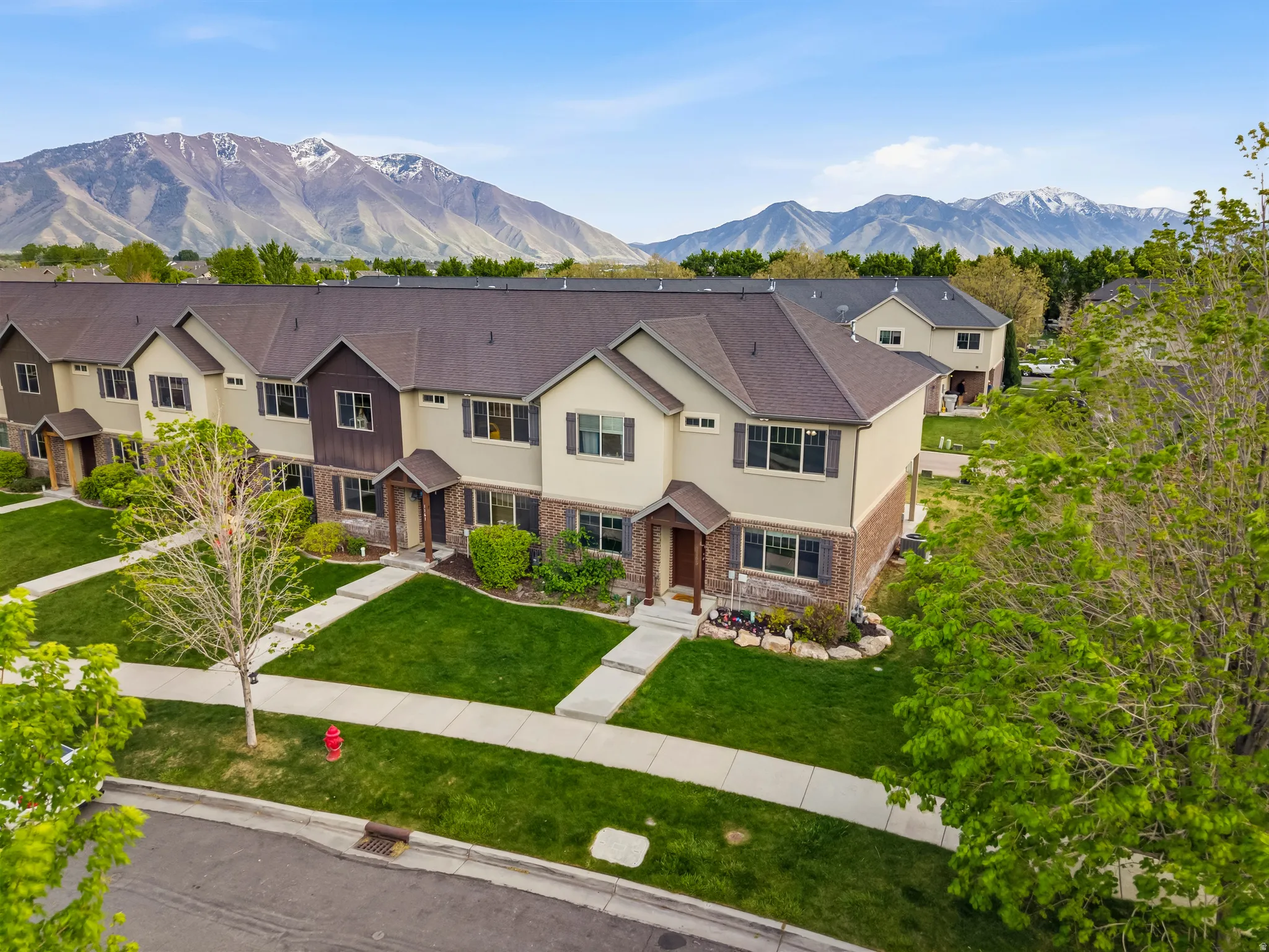 View of front facade with a mountain view, stucco siding, brick siding, and a front lawn