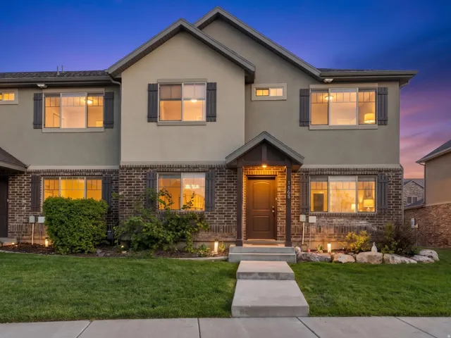 Traditional-style home featuring stucco siding, brick siding, and a lawn