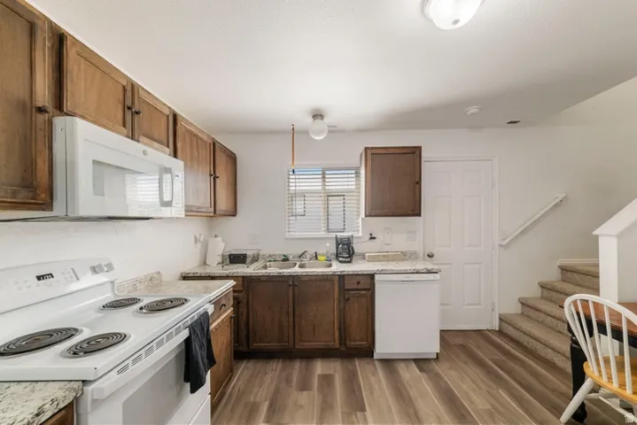 Kitchen featuring white appliances, light countertops, and dark wood-style floors