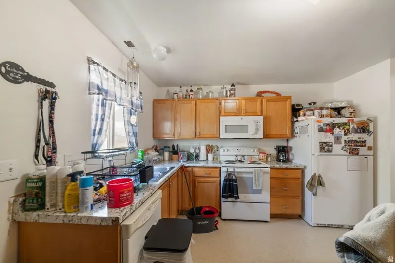 Kitchen with white appliances, light countertops, light flooring, and wood finish cabinetry