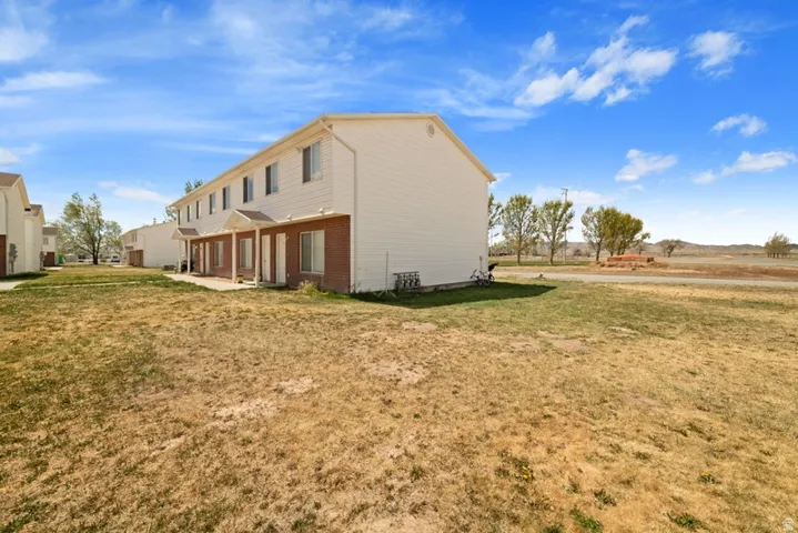 View of property exterior with a patio area, a yard, and brick siding