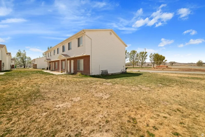 View of property exterior with a patio area, a yard, and brick siding