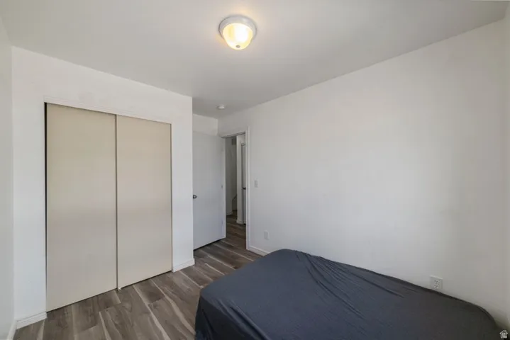 Bedroom with dark wood finished floors and a closet