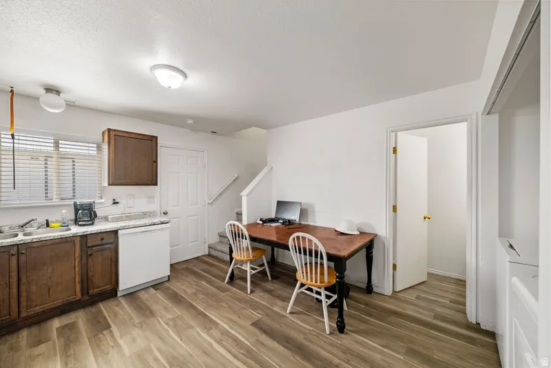 Kitchen with dishwasher, light wood-type flooring, washer / dryer, a desk, and dark wood finish cabinets