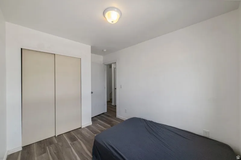 Bedroom with dark wood finished floors and a closet