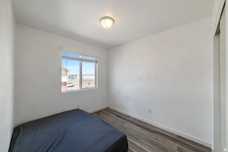 Bedroom with dark wood-style floors and a closet