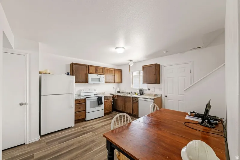 Kitchen with white appliances, light countertops, and dark wood-style flooring