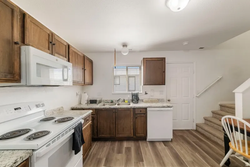 Kitchen featuring white appliances, light countertops, and dark wood-style floors