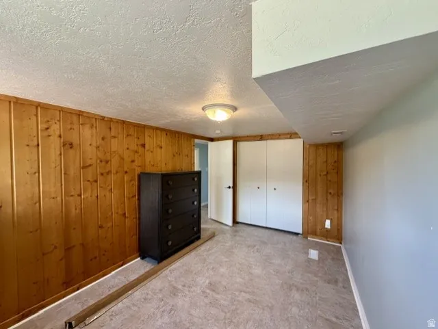 Bedroom #4 featuring wood-paneled walls, light blue painted walls, neutral-toned flooring, and white bifold closet doors