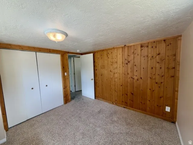 Bedroom #5 with wood paneled wall and white closet doors