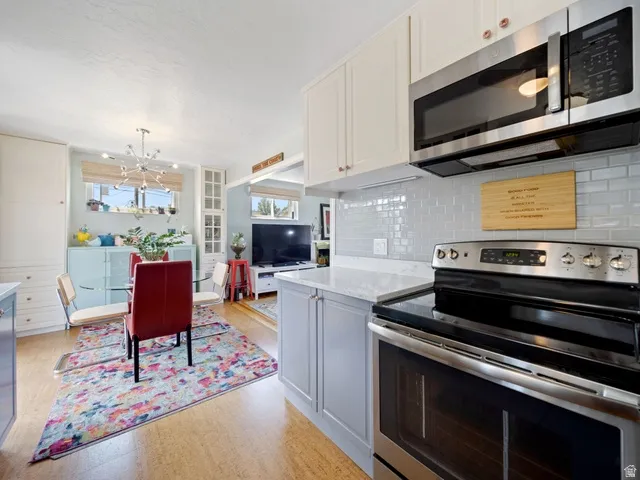 Kitchen featuring stainless steel appliances, a chandelier, quartz countertops, and tasteful backsplash