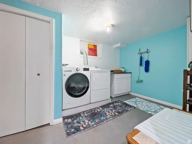 Laundry room featuring a textured ceiling, washing machine and clothes dryer included , and cabinet space