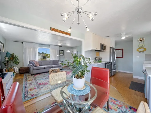 Dining area with ceiling fan, light wood-style floors, and hanging lights