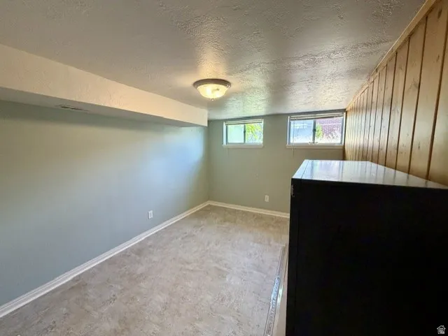 Bedroom #4 featuring light blue colored walls, wood-paneled accent wall, two horizontal windows allowing natural light