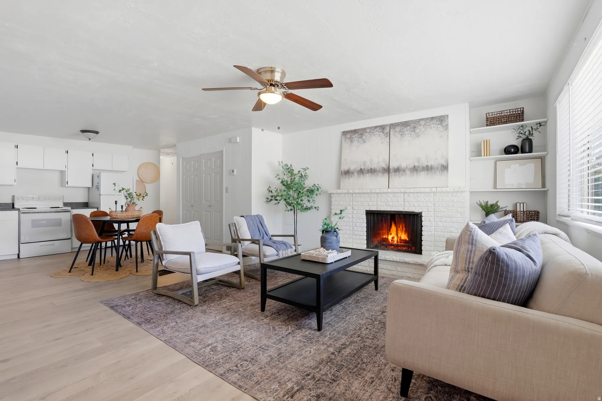 Living area with light wood-style flooring, a ceiling fan, and a fireplace