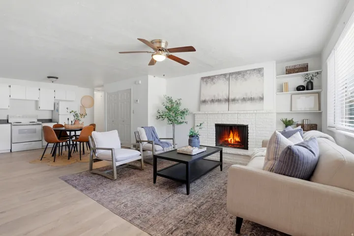 Living area with light wood-style flooring, a ceiling fan, and a fireplace