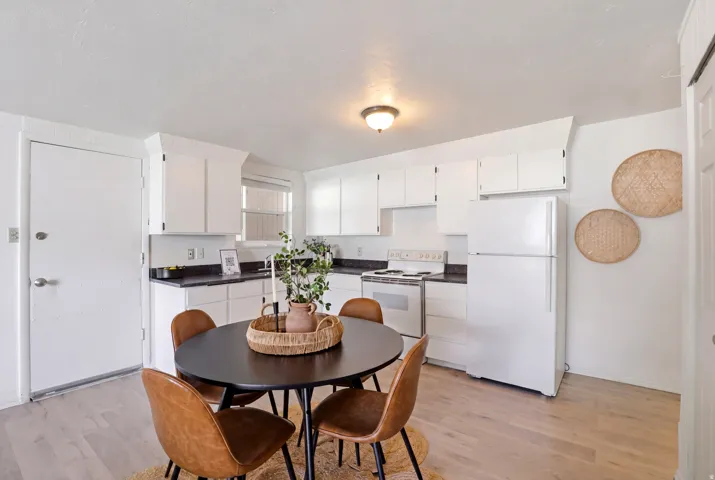 Kitchen featuring white appliances, dark countertops, and white cabinets