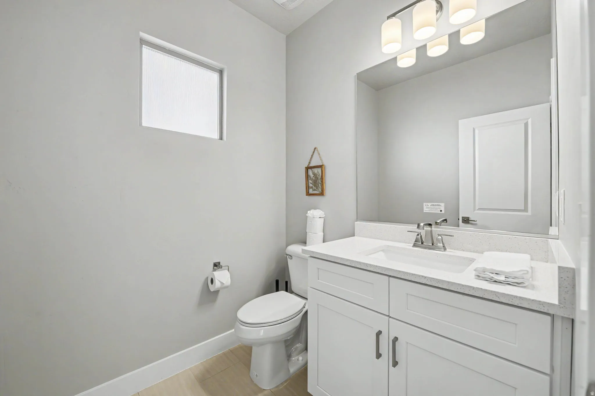White vanity with brushed nickel hardware, integrated rectangular sink, and light-toned countertop