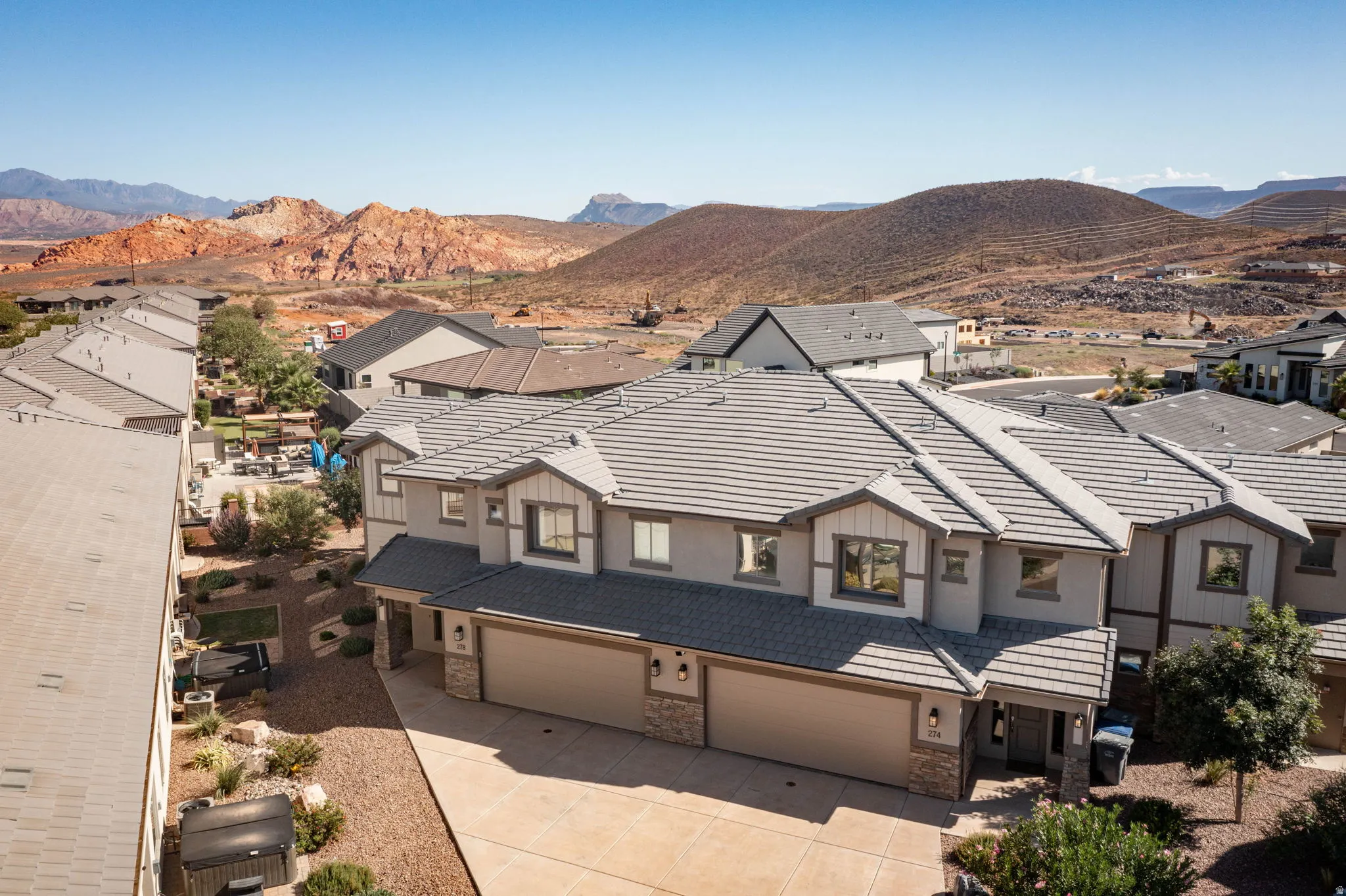 Contemporary townhouse exterior with a tiled roof, multi-car garage, and desert landscaping
