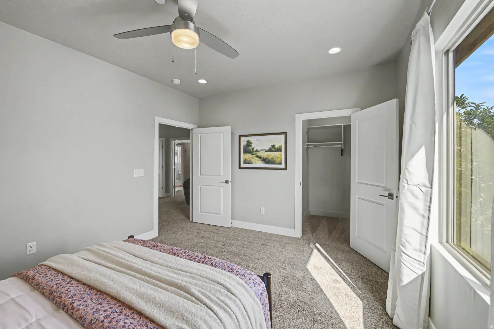 Carpeted room featuring a ceiling fan with integrated lighting, recessed lighting, and a window