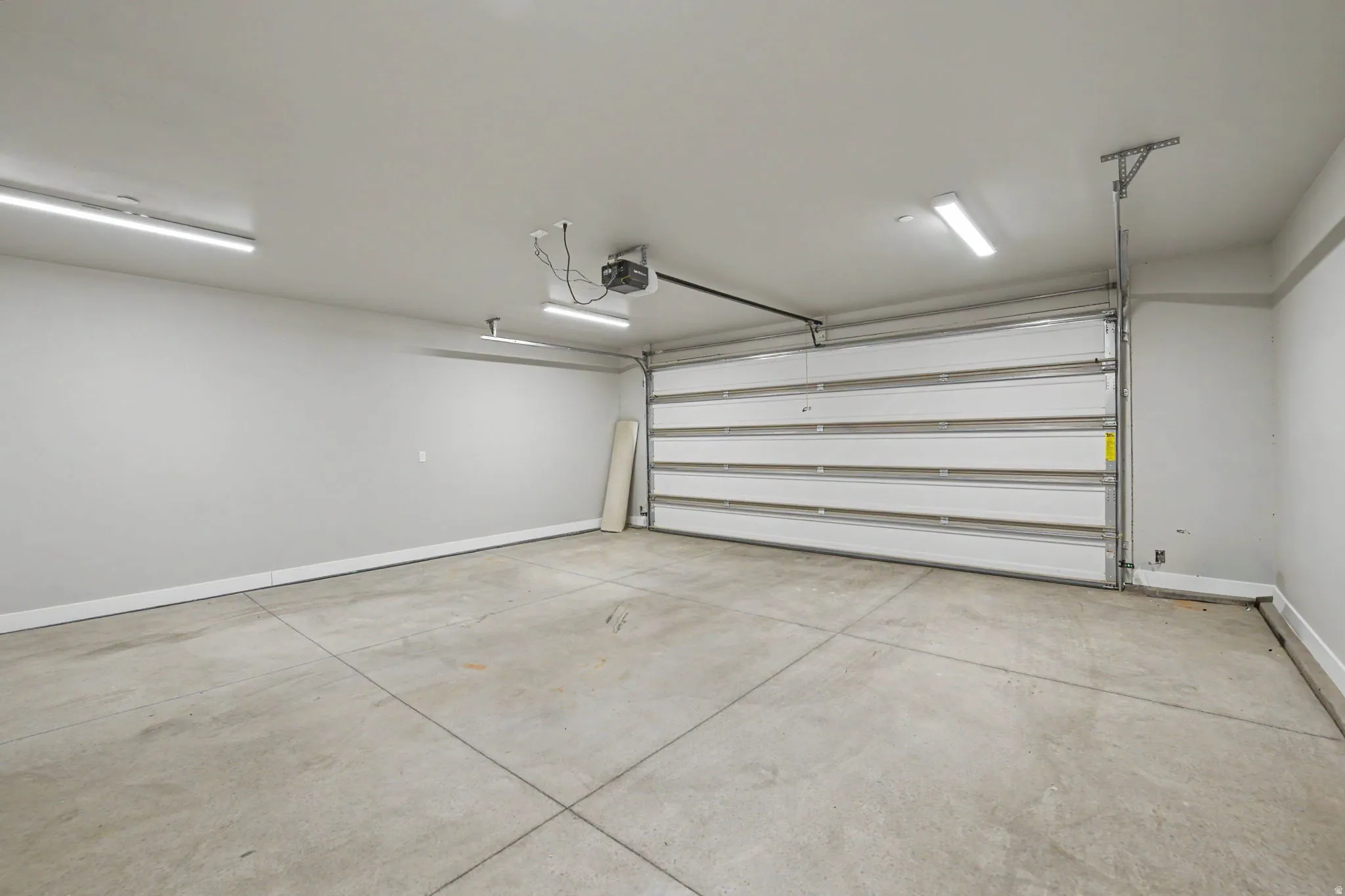 Attached garage space with a concrete floor, overhead lighting, and an automatic garage door opener