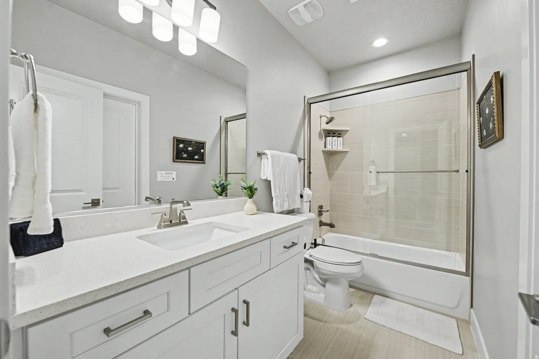 Vanity with a light-toned countertop, white cabinetry with dark hardware, and a single undermount sink
