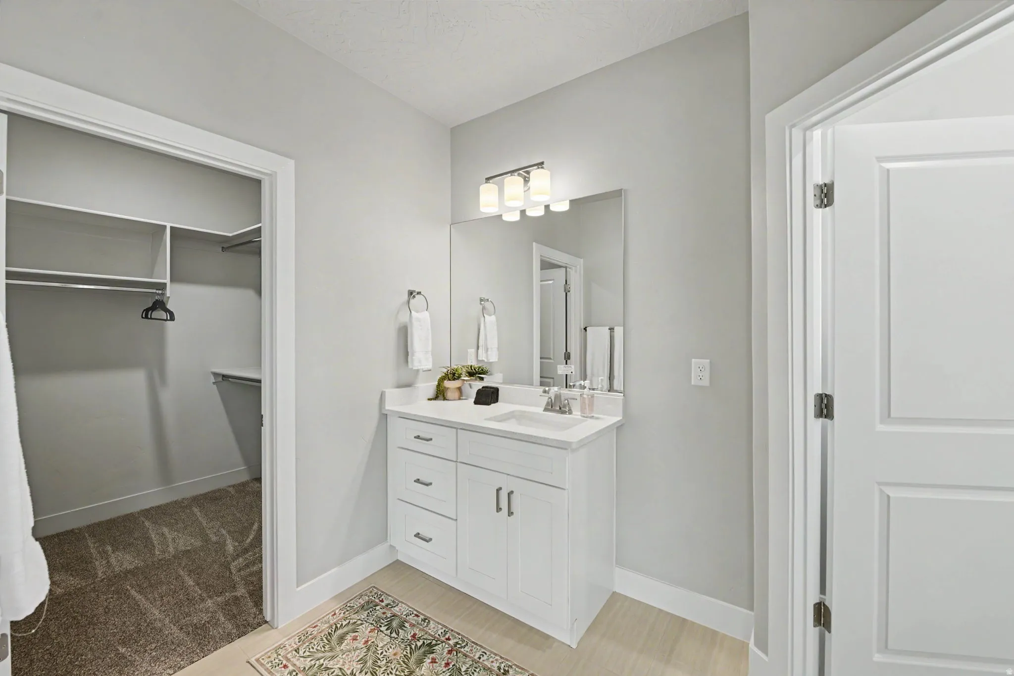 White vanity with a quartz countertop, under-mount sink, and chrome faucet