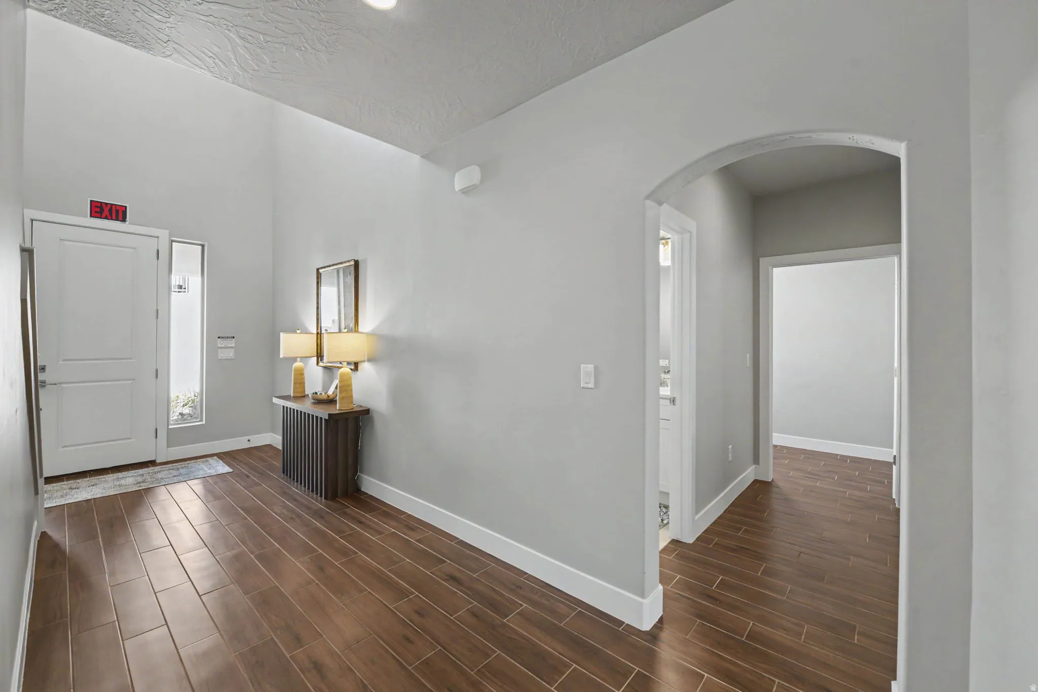Bright, open entryway showcasing rich wood-finish flooring throughout, crisp white walls, and clean architectural lines