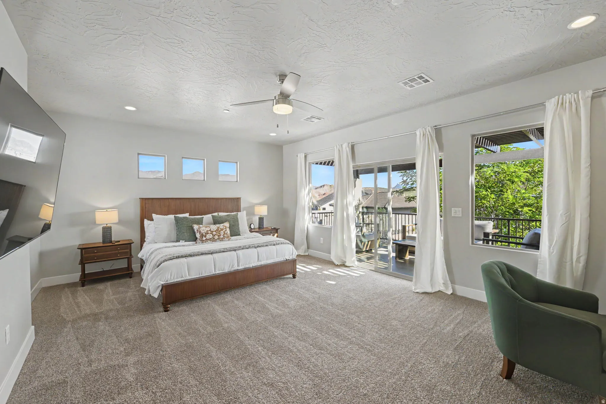 Expansive carpeted room with multiple windows, recessed lighting, and a ceiling fan