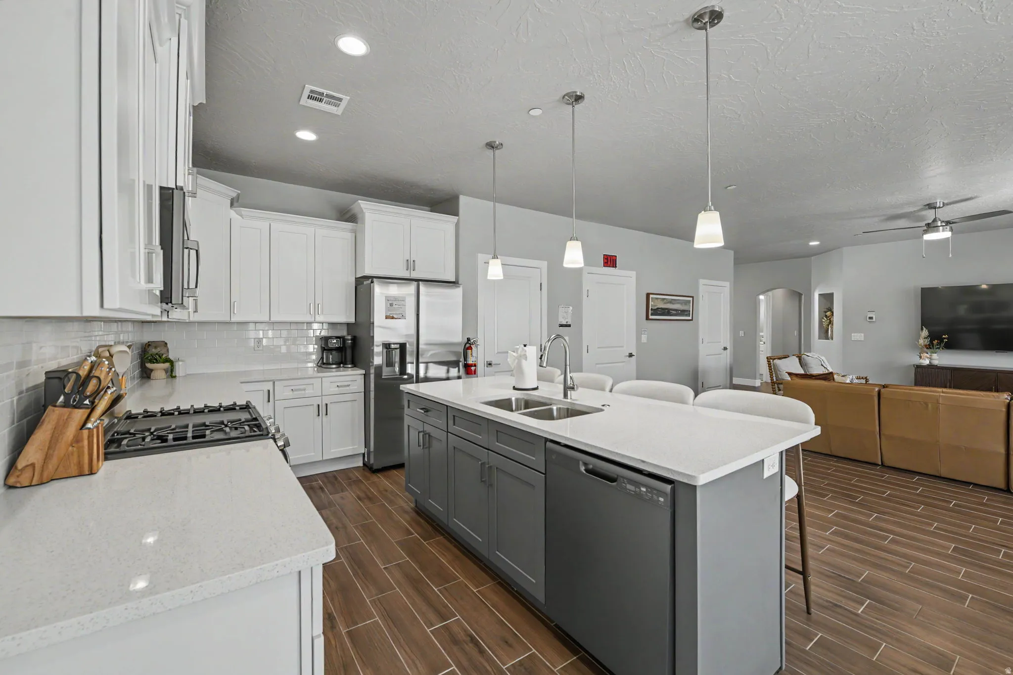 Kitchen featuring white upper cabinetry, gray lower cabinetry, light-toned countertops, a subway tile backsplash, and stainless steel appliances