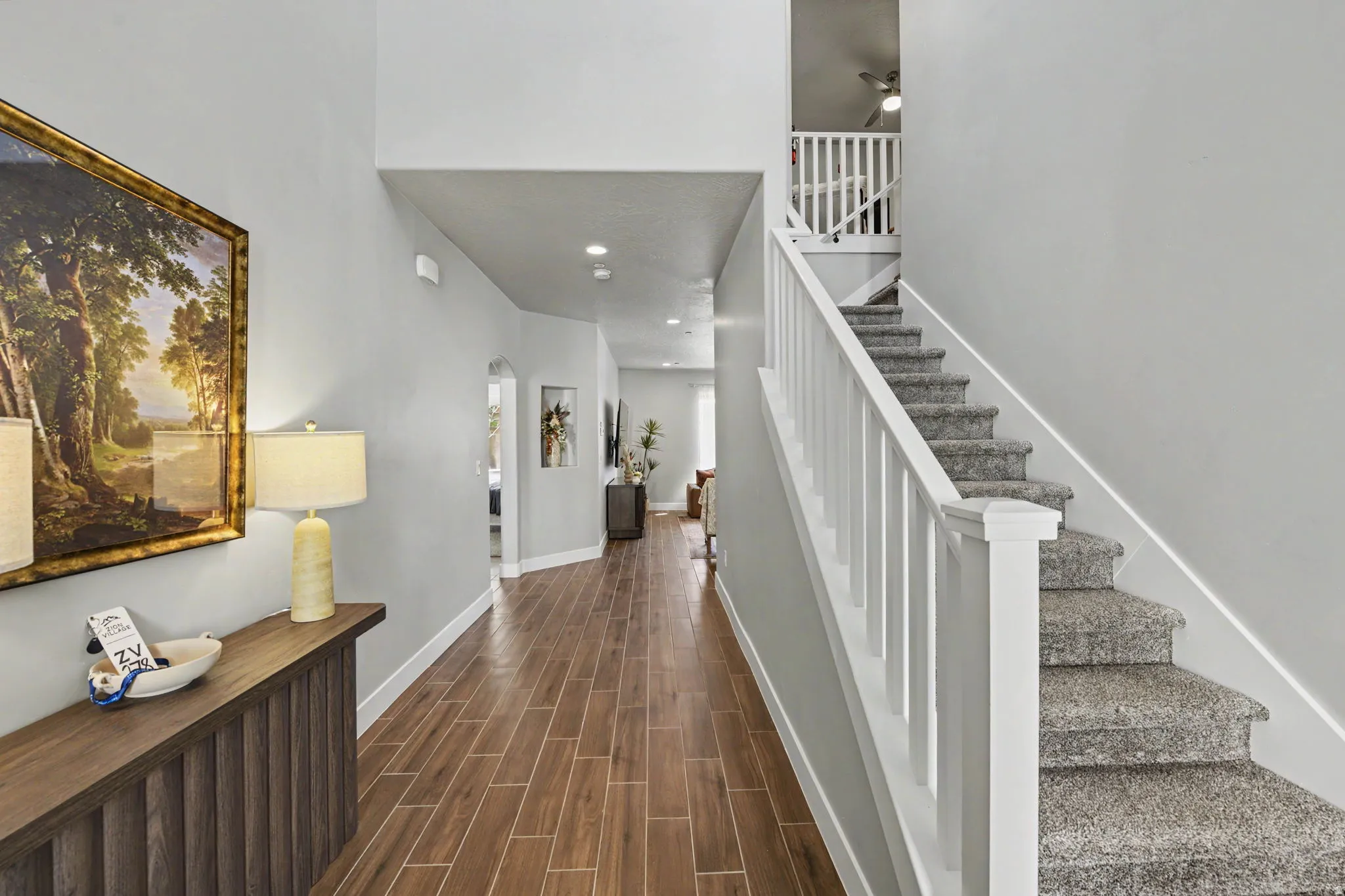 Elegant foyer showcasing hardwood flooring, white painted railings, and a curved staircase with carpeted treads
