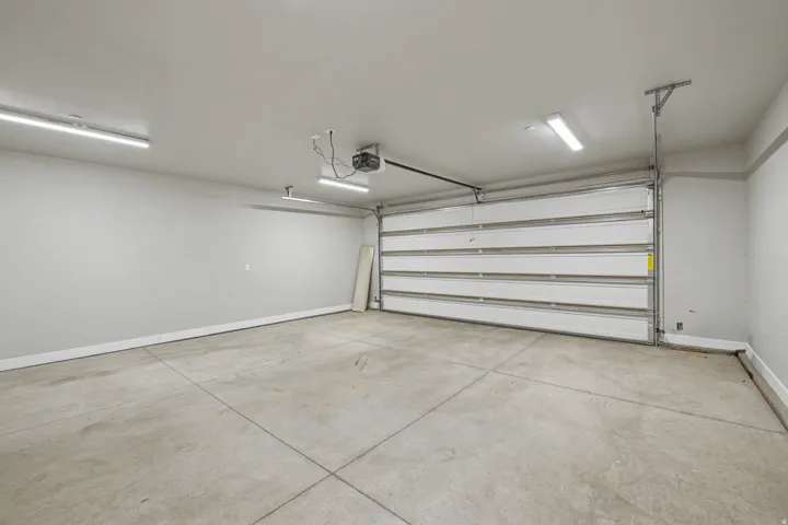 Attached garage space with a concrete floor, overhead lighting, and an automatic garage door opener