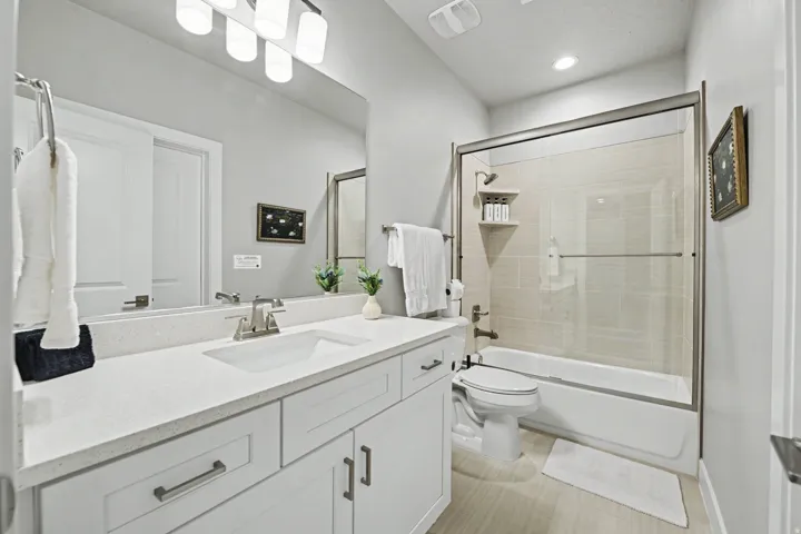 Vanity with a light-toned countertop, white cabinetry with dark hardware, and a single undermount sink