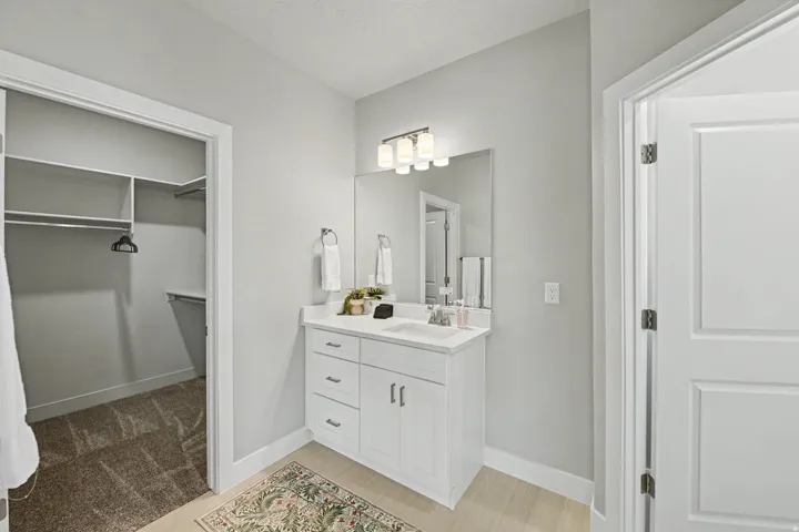 White vanity with a quartz countertop, under-mount sink, and chrome faucet