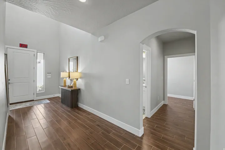 Bright, open entryway showcasing rich wood-finish flooring throughout, crisp white walls, and clean architectural lines