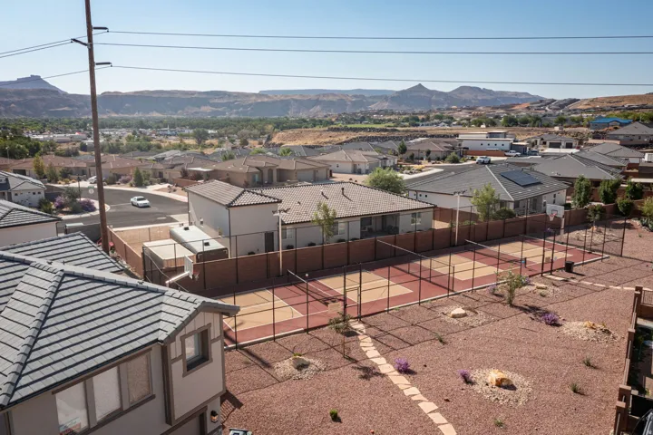 Multi-sport court within a fenced property, surrounded by desert landscaping and a stone pathway