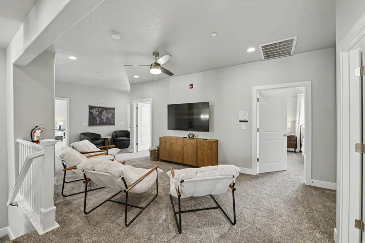 Recessed lighting, ceiling fan, carpeted flooring, white trim, and a white interior railing