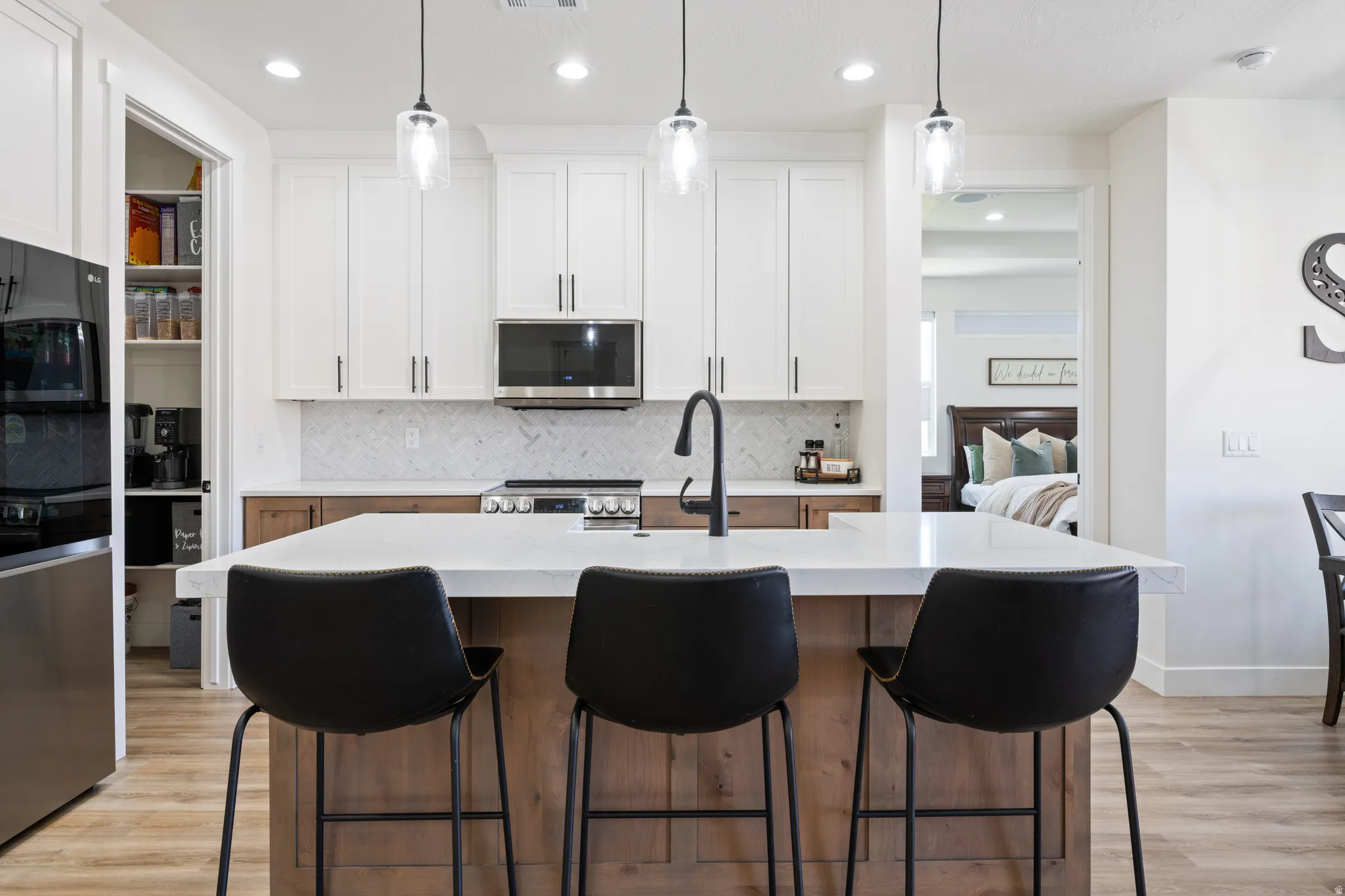 Two tone kitchen featuring a kitchen bar, tasteful backsplash, stainless steel appliances, pendant lighting, and two tone color scheme