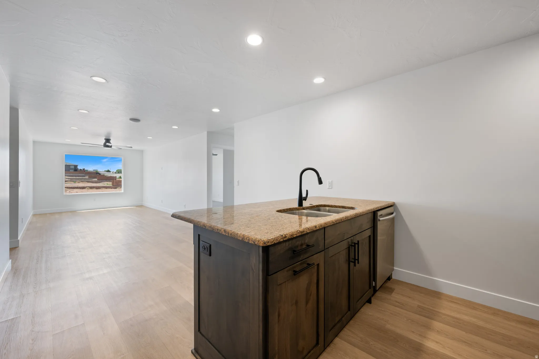 Kitchen featuring a peninsula, dark wood finish cabinets, light wood-style floors, light stone countertops, and open floor plan