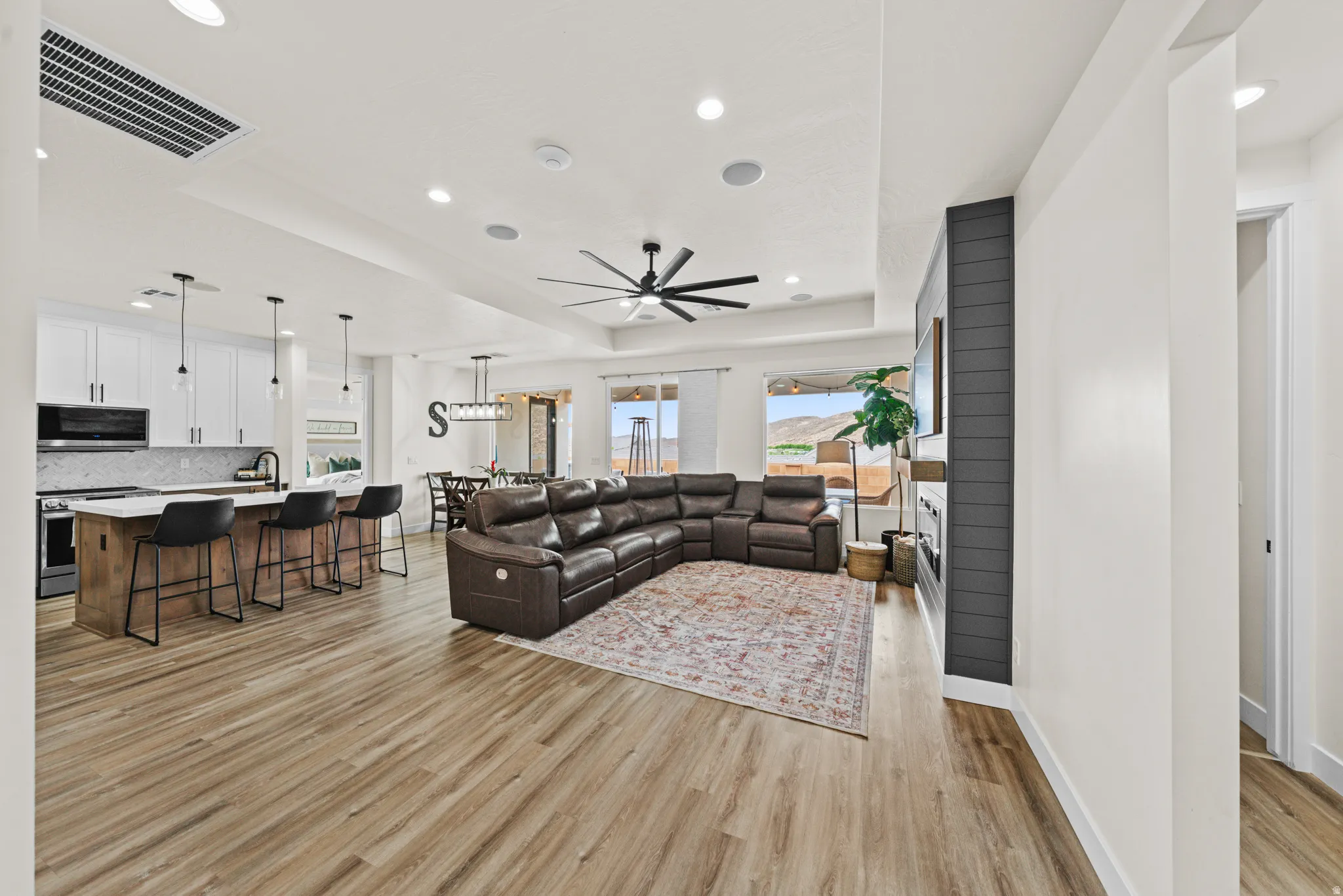 Living room with a ceiling fan, light wood-style flooring, a tray ceiling, and recessed lighting