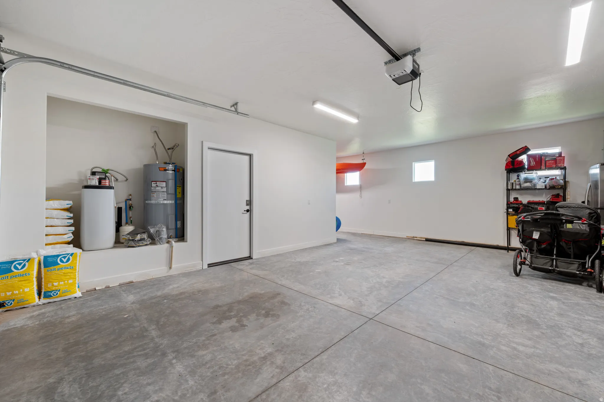 Garage featuring secured water heater and a garage door opener