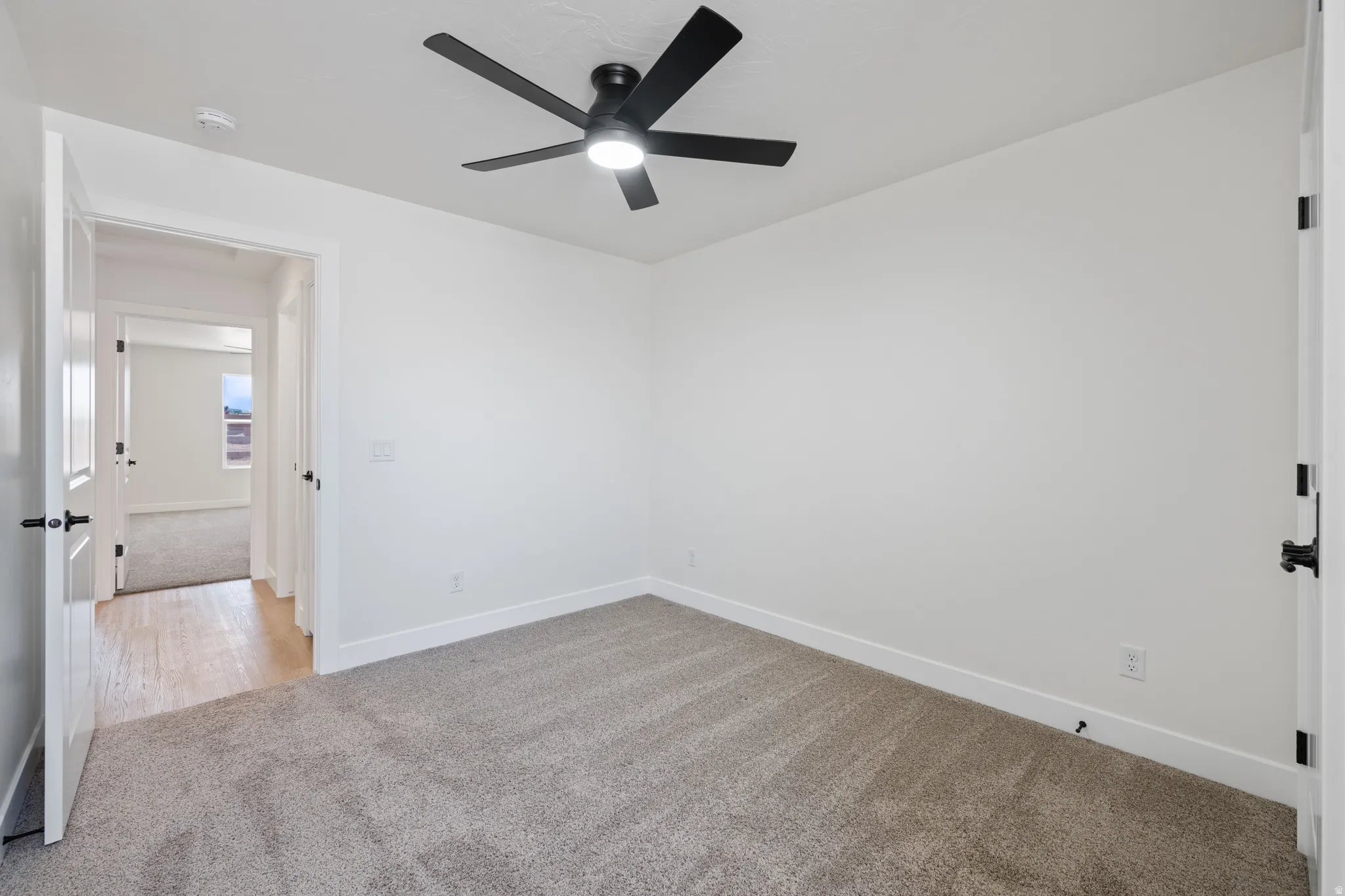 Empty room featuring light carpet and a ceiling fan