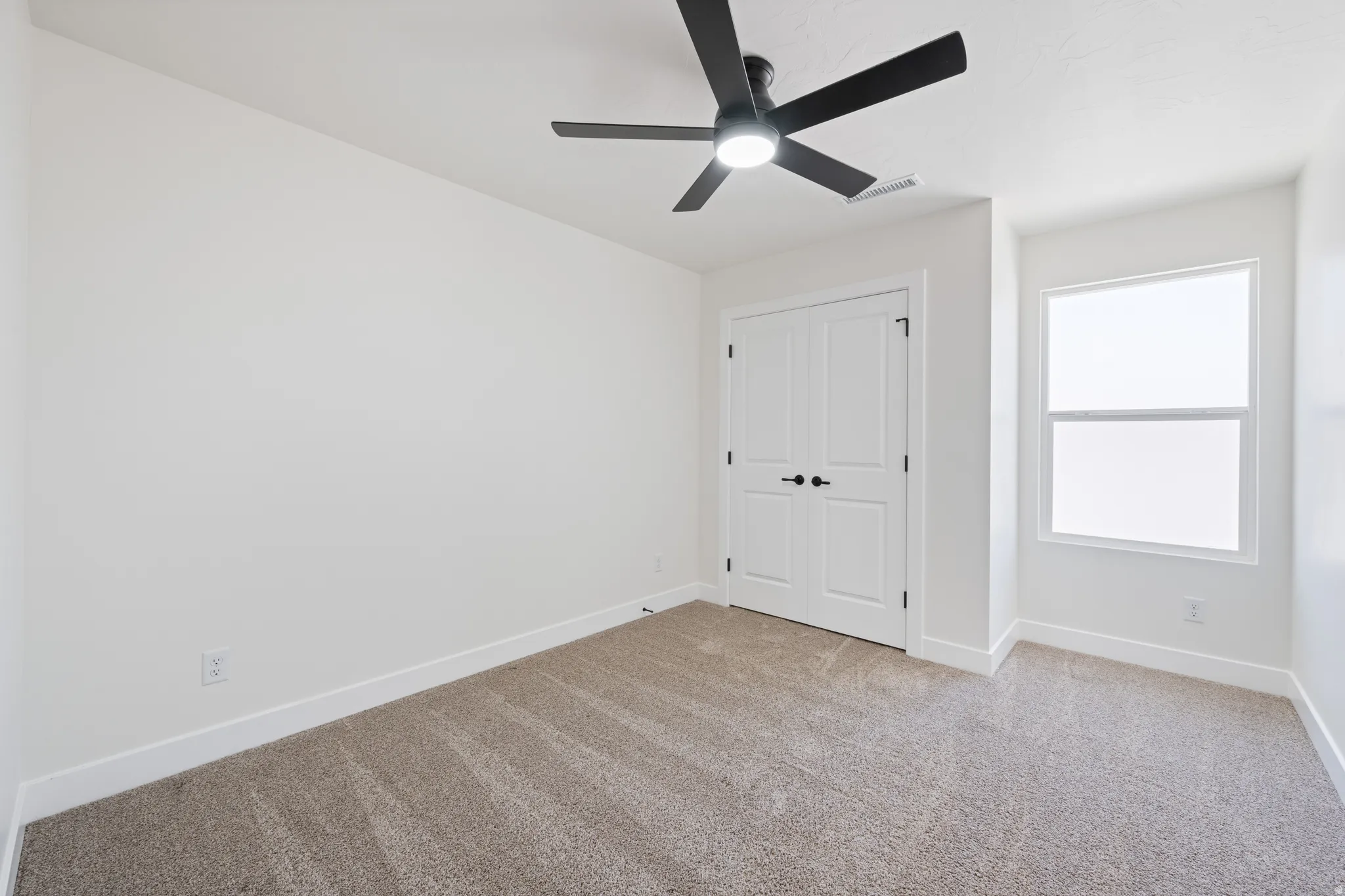 Unfurnished bedroom with light colored carpet, ceiling fan, and a closet