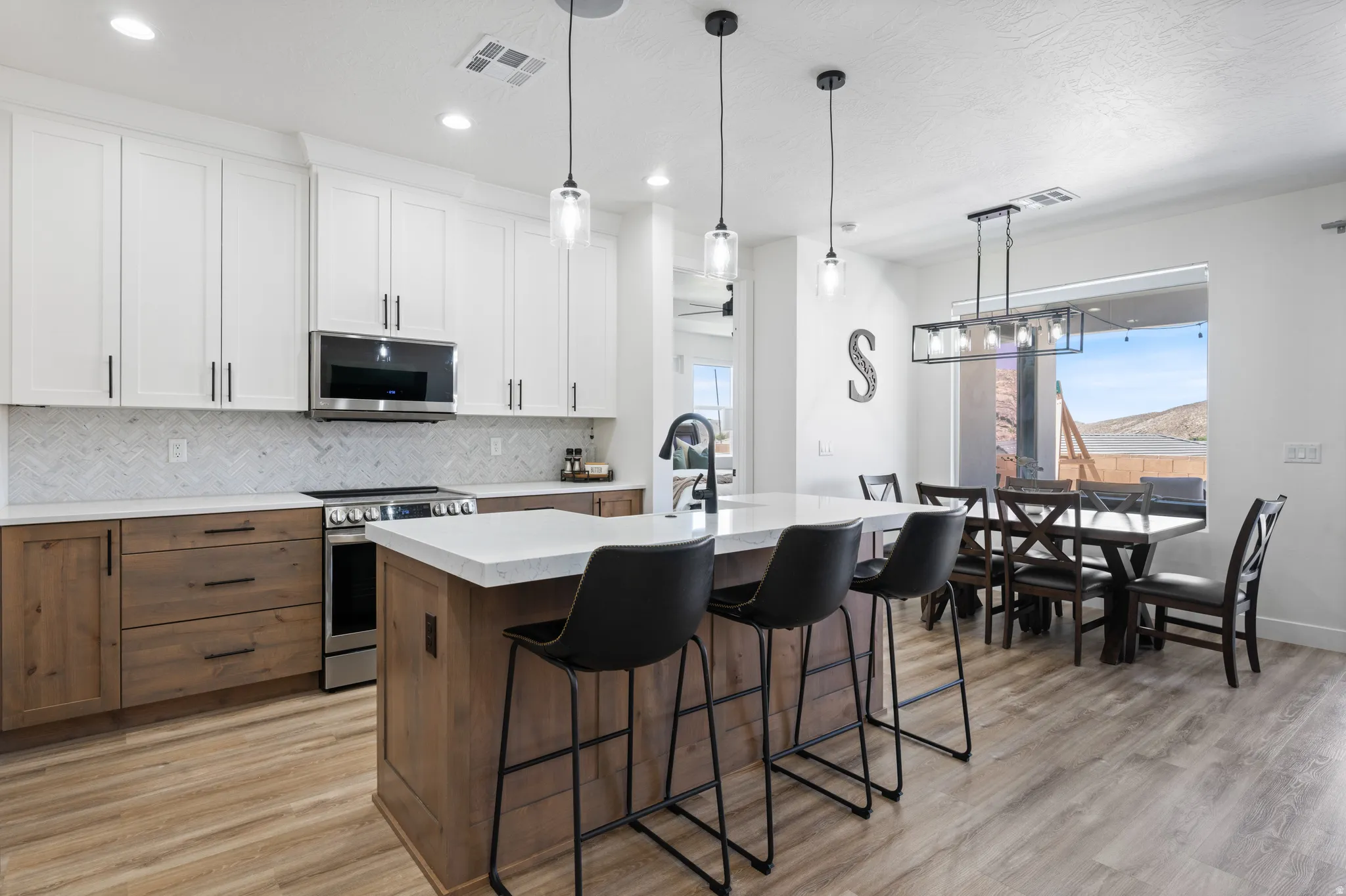 Dual tone kitchen featuring two tone color scheme, a kitchen island with sink, tasteful backsplash, a breakfast bar, and stainless steel appliances
