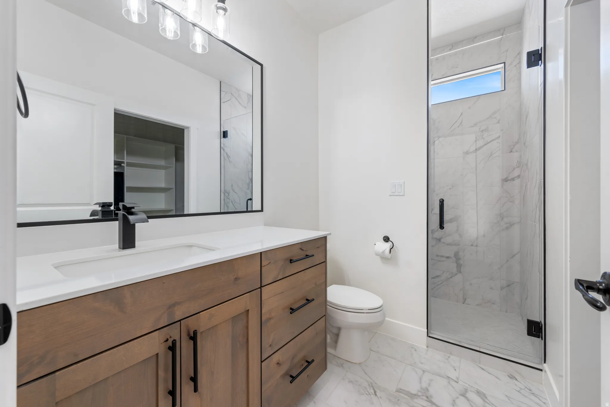 Full bathroom featuring a marble finish shower, vanity, and light marble finish floors