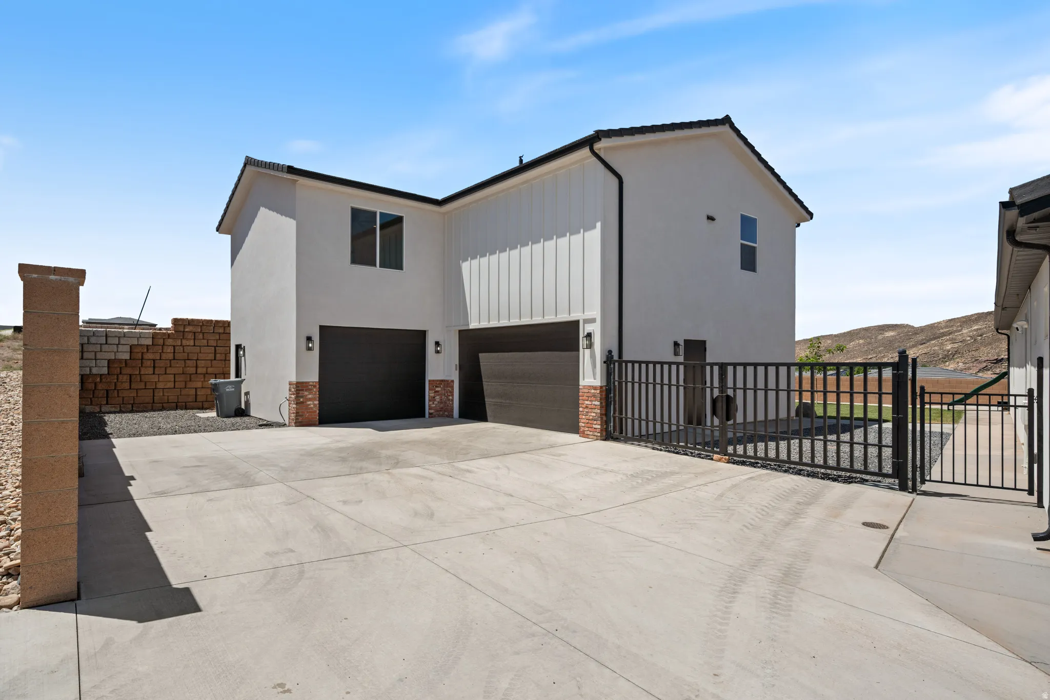 View of side of property featuring a garage, a gate, driveway, and board and batten siding