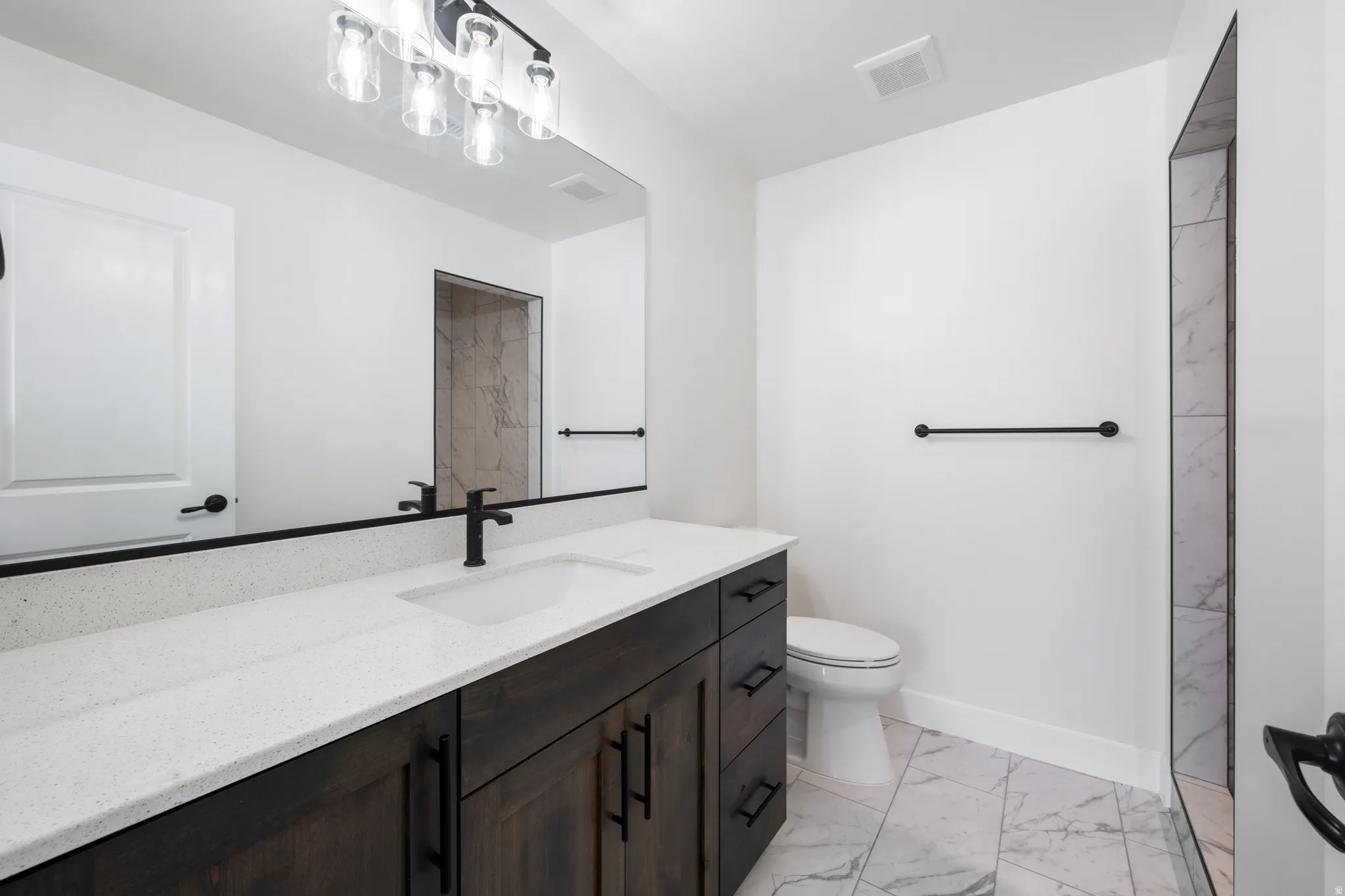 Bathroom featuring light marble finish flooring, vanity, and a marble finish shower
