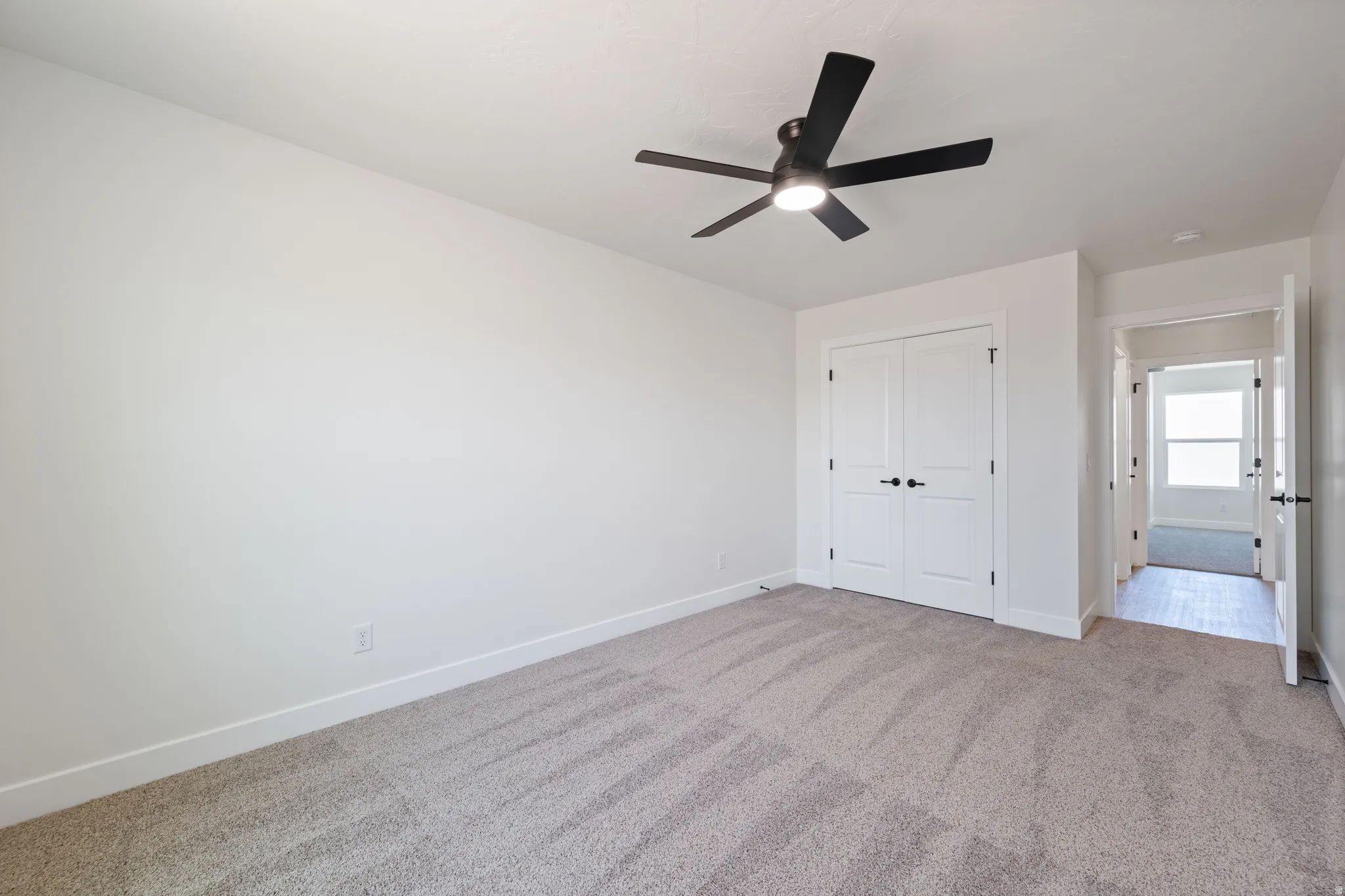 Unfurnished bedroom with light carpet, a ceiling fan, and a closet