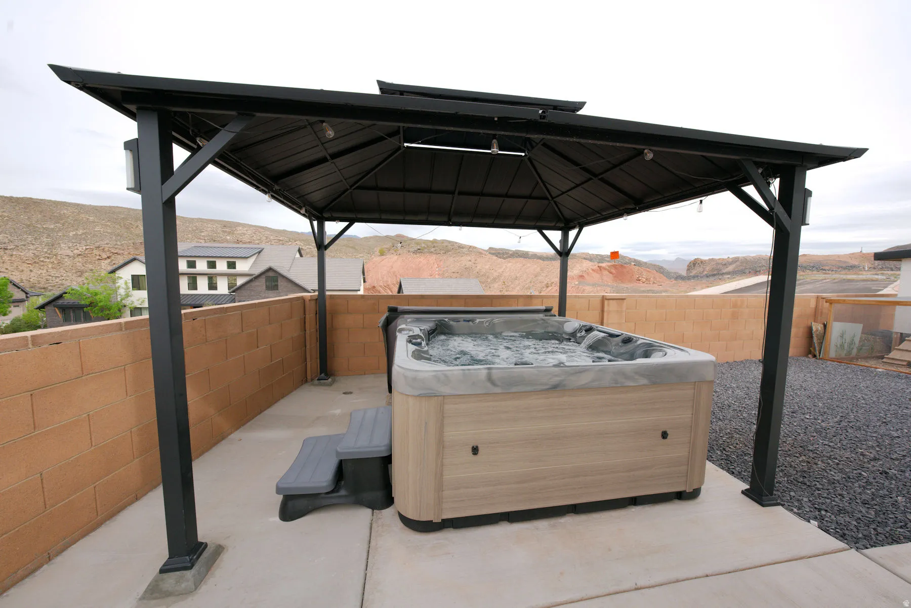 Fenced backyard featuring a hot tub, a mountain view, a gazebo, and a patio area
